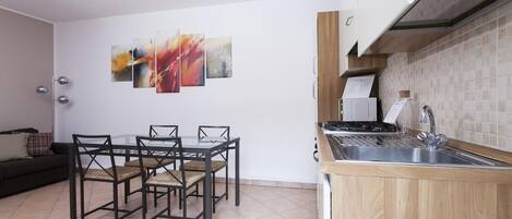 Cozinha compacta com área de jantar, com fogão moderno, pia e mesa com cadeiras.