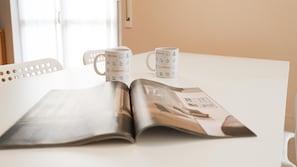 A table with two white mugs labeled "Italianway" and an open magazine. - Italianway Easy - Dei Tulipani 4 (Milan)