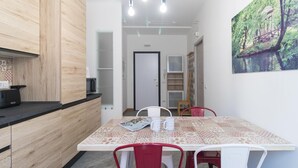 A modern kitchen with wooden cabinets, a black countertop, and a dining area with a patterned tablecloth. - Italianway Easy - Piceno 23 A (Milan)