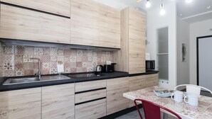 A modern kitchen with wooden cabinets, a patterned backsplash, and a dining area with a table and chairs. - Italianway Easy - Piceno 23 A (Milan)