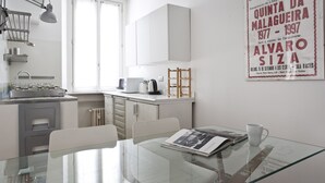 Une cuisine moderne avec une table en verre, des meubles blancs et une affiche accrochée au mur.