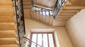 A grand staircase with ornate metal railings and a view of a window at the bottom.