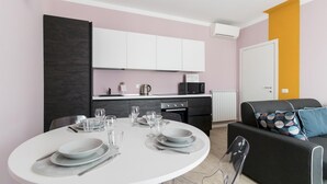 A modern kitchen with white cabinets, a black countertop, and a built-in oven. - Italianway Comfort - Buenos Aires 65 A (Milan)