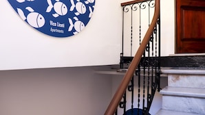 A staircase with a metal railing and a circular sign on the wall. - Liceti 5 A (Rapallo)