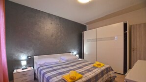 A bedroom with a bed, nightstands, a wardrobe, and a bathroom.