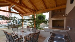 An outdoor patio with a table and chairs, a sink, and a brick oven.