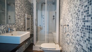 Ein modernes Badezimmer mit einer gläsernen Duschkabine, einem weißen Waschbecken und einer Toilette.