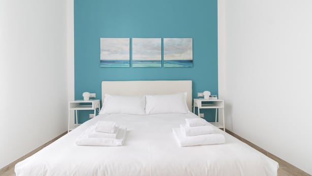 A hotel room with a large bed, white bedding, two nightstands, and a blue accent wall. - Italianway Comfort - Borsieri 25 A (Milan)