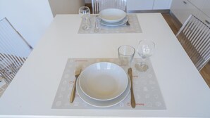 Una mesa de comedor dispuesta con platos, vasos y cubiertos.