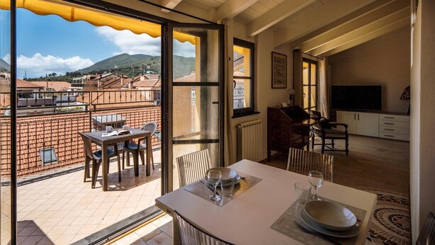 Un comedor con una mesa dispuesta para dos, vistas a la ciudad y un balcón con mesa y sillas.