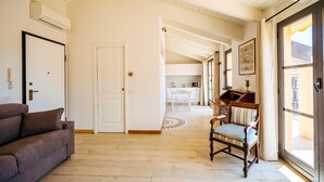 Un salón amplio con un sofá, una silla de madera y un ventanal grande.