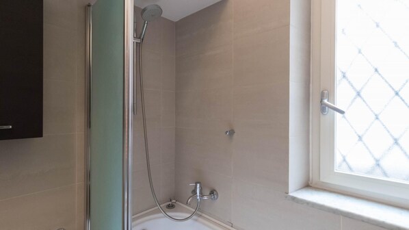 A bathroom with a shower, a bathtub, and a window with a diamond-patterned blind. - Italianway Comfort - Torino 66 (Milan)