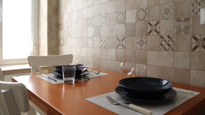 Un comedor con mesa de madera, dos sillas y un salpicadero de azulejos.