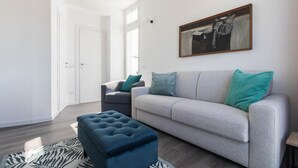 Un saló modern amb un sofà gris, un pouf blau i una catifes amb dibuixos de zebra.