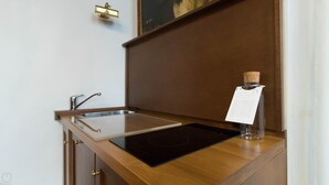 Una cocina con un lavamanos de acero inoxidable, una placa de inducción negra y una botella de aceite de oliva en la encimera.