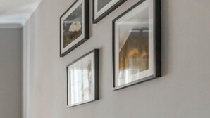 Una habitación con cama, mesita de noche y una pared decorada con cuadros.
