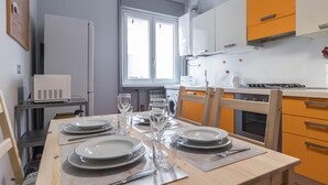 Comedor con una mesa dispuesta para cuatro, con platos, vasos y cubiertos.