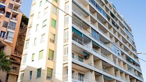 A multi-story building with balconies, a visible entrance, and a clear sky.