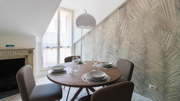 Comedor con una mesa redonda dispuesta para cuatro personas, chimenea y pared con diseño.