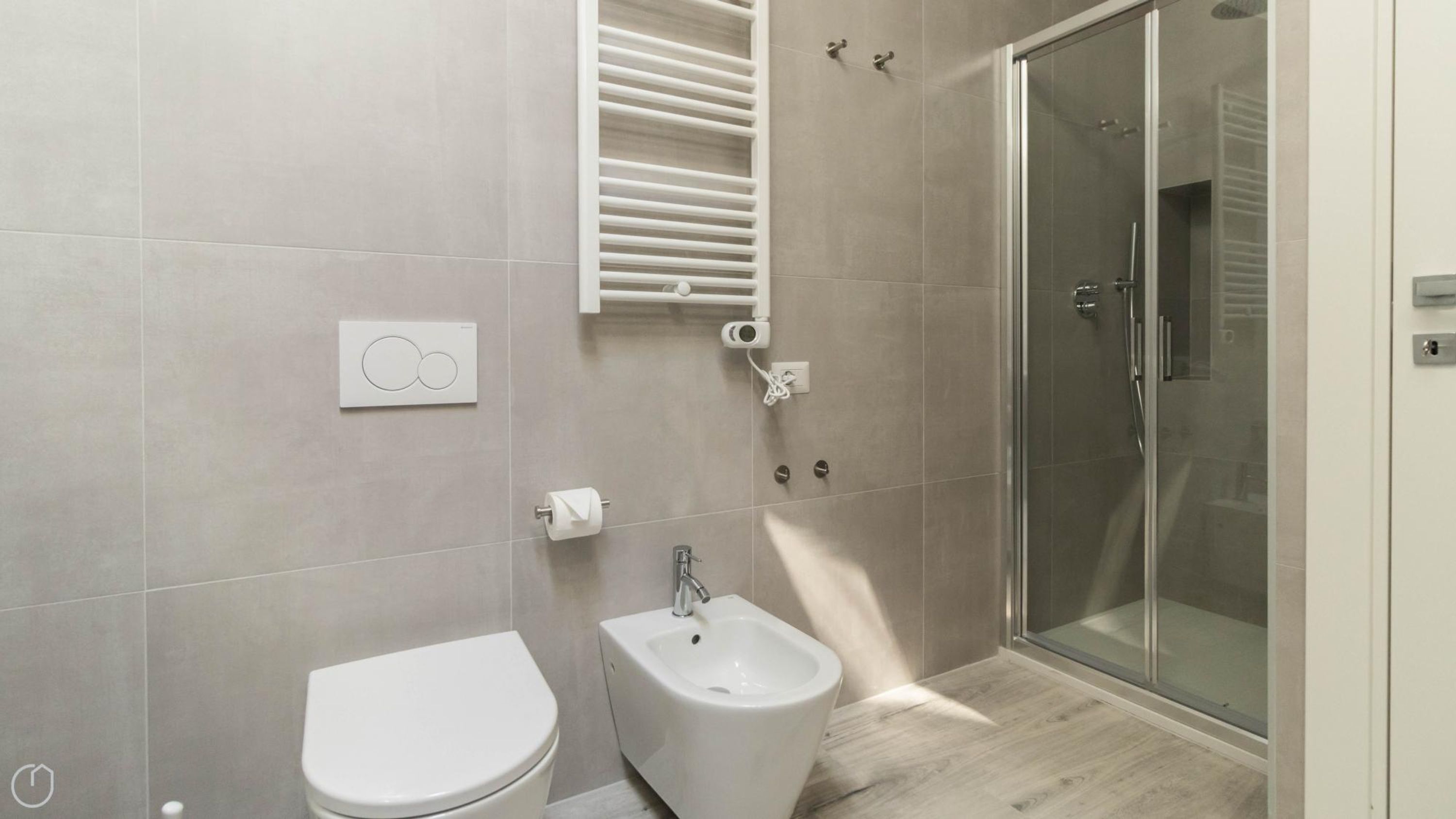 Un baño moderno con inodoro, bidé y cabina de ducha de vidrio.