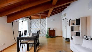 A spacious living area with a wooden ceiling, a dining table with chairs, a white sofa, and a bookshelf. - Colombo 4 (Villasanta)