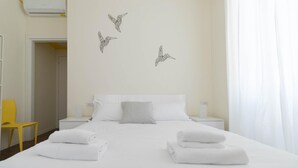 A hotel room with a neatly made bed, two bedside tables, a striped pillow, and wall art of birds. - Italianway Easy - Buenos Aires 65 B (Milan)