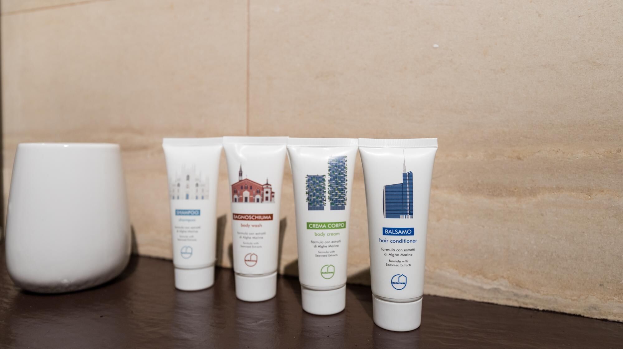 Four tubes of hair care products on a wooden surface against a beige wall.