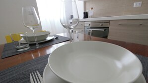 Un tavolo apparecchiato con una ciotola bianca, due bicchieri da vino e una forchetta.