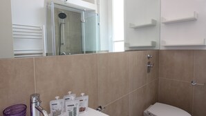 Un bagno con box doccia in vetro, un water e un lavandino con articoli da toilette.