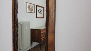 Una stanza con un termosifone, una cassettiera in legno e due quadri appesi al muro.