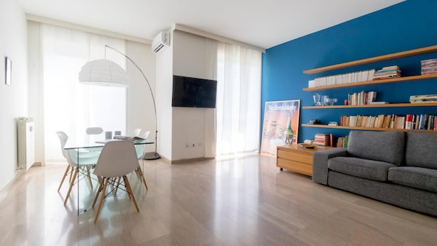 Una sala de estar moderna con comedor, una estantería y un televisor de pantalla plana.