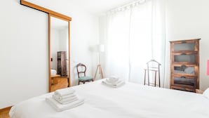 Una habitación de hotel con una cama grande, un armario de madera, una silla y una lámpara de pie.
