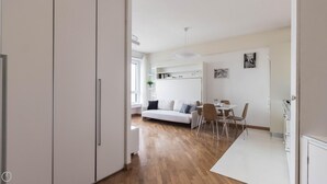 A modern, open-plan living space with a white sofa, dining table, and chairs. - Italianway Easy - Biancamano 2 (Milan)