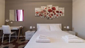 A hotel room with a bed, two bedside tables, a desk, a chair, a mirror, and a large floral artwork on the wall. - Italianway Comfort - Borsieri 11 B (Milan)