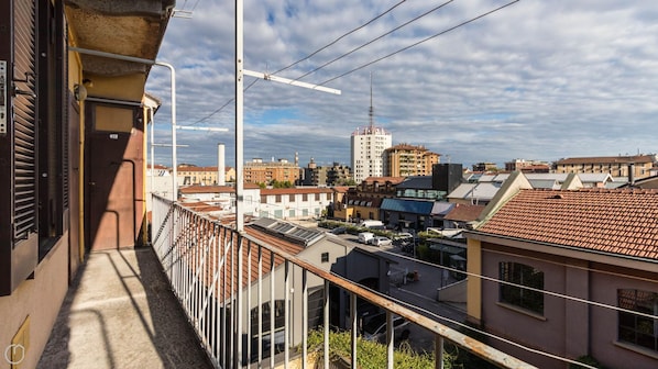 A balcony with a view of a cityscape, including buildings and a tower.