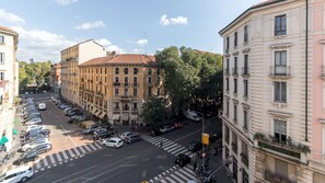 A street view with a row of parked cars, a pedestrian crossing, and buildings with balconies and windows. - Italianway Comfort - Vincenzo Monti 29 B (Milan)