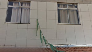 Un edifici amb façana de rajoles i dues finestres amb cortines.