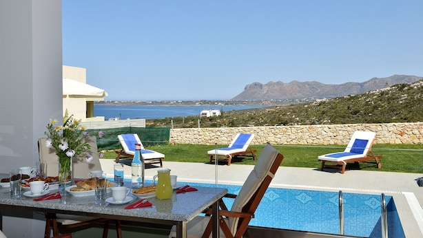 A poolside dining area with a table set for two, overlooking a mountainous landscape and the sea. - Modern Villa with Private Pool in Chania (Chania)