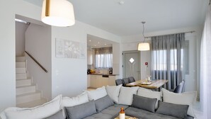 A modern living room with a grey sofa, a wooden coffee table, and a dining area with a table and chairs. - Modern Villa with Private Pool in Chania (Chania)