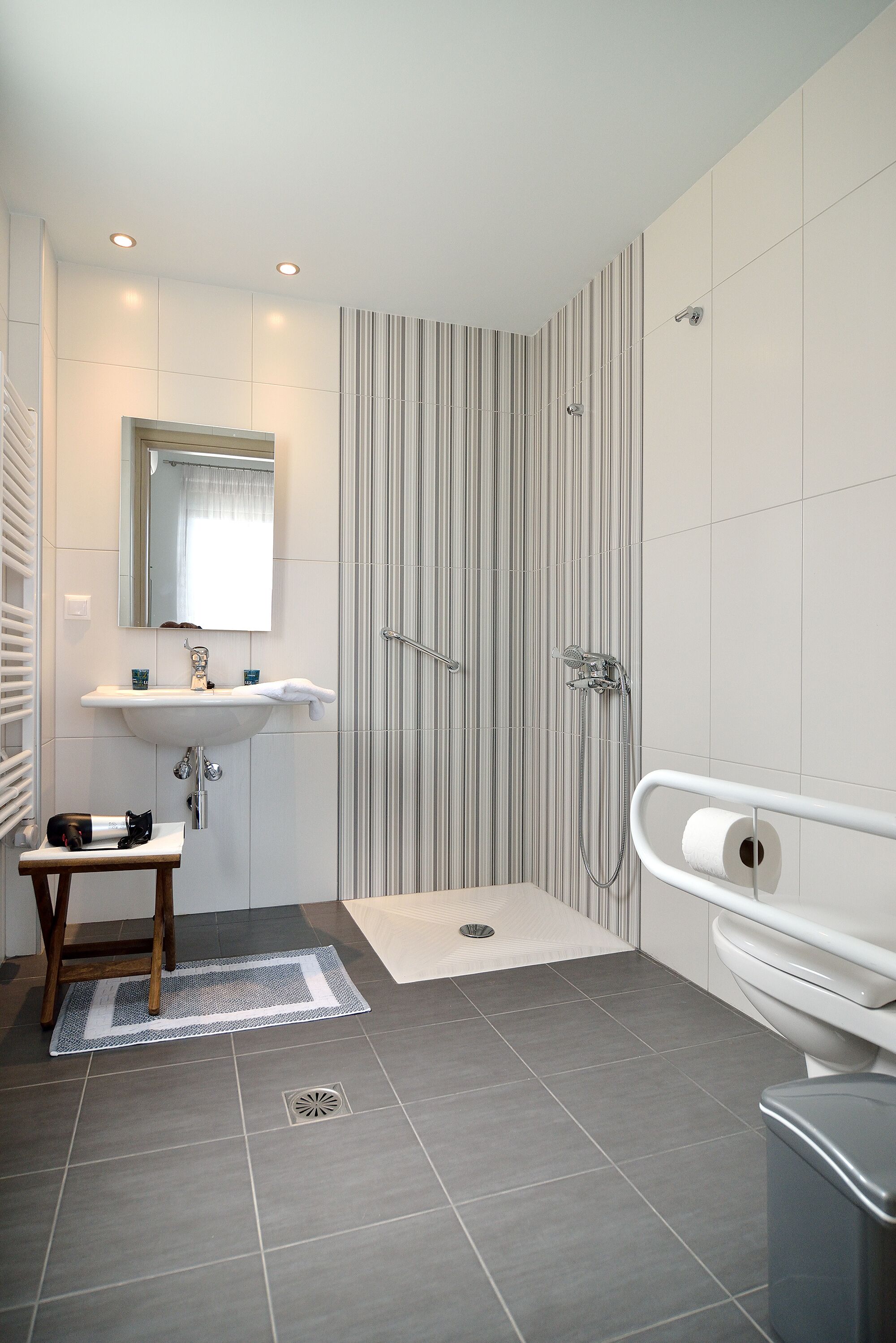 A modern bathroom with a sink, mirror, shower, and toilet.