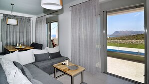 A modern living room with a grey sofa, a wooden coffee table, and a view of the sea through large sliding glass doors. - Modern Villa with Private Pool in Chania (Chania)