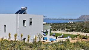 A modern building with a pool area, including lounge chairs and a view of the sea. - Modern Villa with Private Pool in Chania (Chania)
