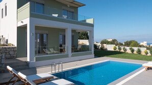 A modern two-story house with a swimming pool, outdoor seating, and a view of the sea. - Modern Villa with Private Pool in Chania (Chania)
