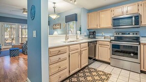 A kitchen with wooden cabinets, stainless steel appliances, and a patterned rug.