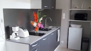 Una cocina moderna con gabinetes grises, microondas integrado, cafetera y un florero con flores.