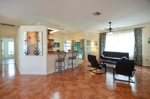 Relax in this stylish living area with a sofa set, dining area, and large painting.