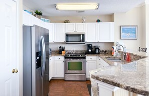 Enjoy cooking in this fully equipped kitchen with a refrigerator, microwave, oven, coffee maker, and sink.