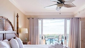 A hotel room with a large bed, a ceiling fan, a balcony with a pool, and a view of the city. - Oceanfront Villa w/Pool Beach Access Hilton Head (Hilton Head Island)