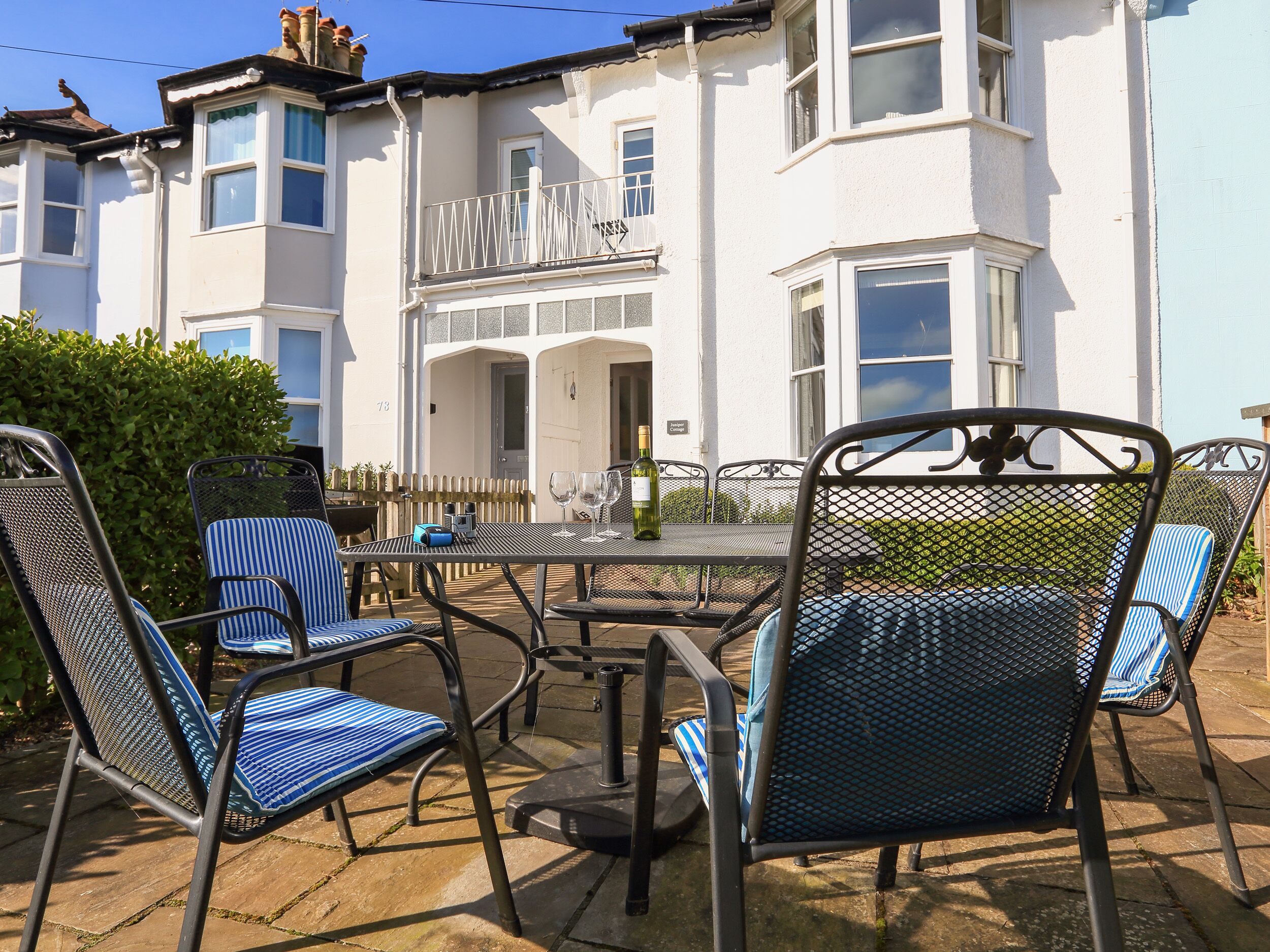 A patio area with metal chairs and tables, a white building with bay windows, and a sign indicating 'Guest Cottage'.