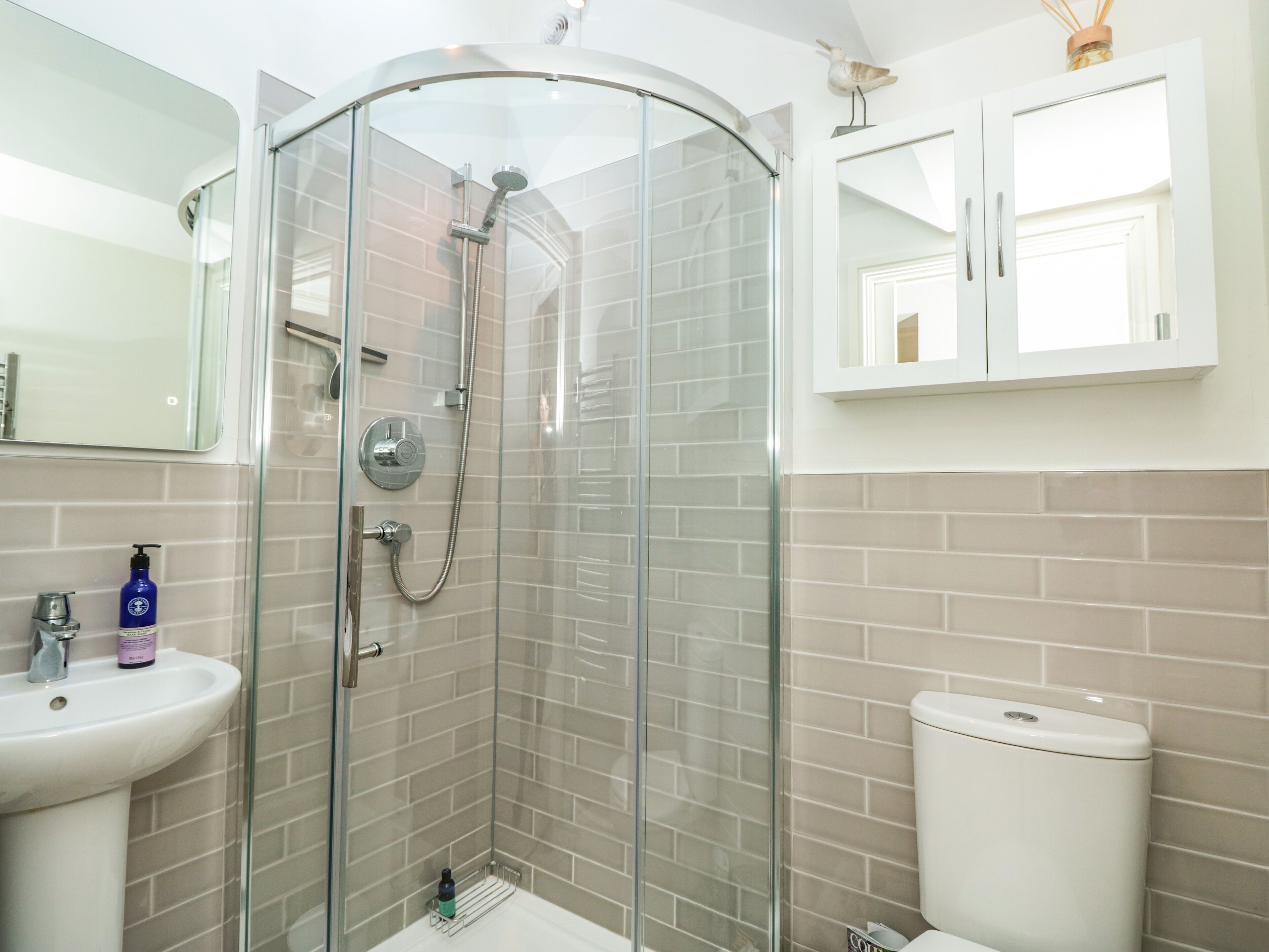 Un baño moderno con ducha envuelta en vidrio, un lavamanos y un inodoro.